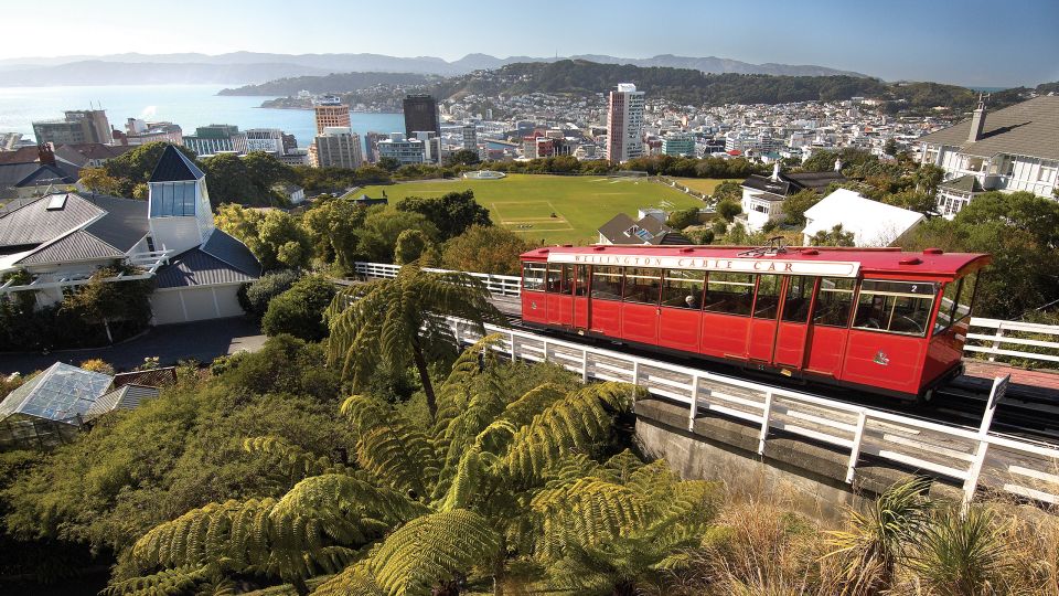 A Train On A Steel Track With Wellington Cable Car In The Background